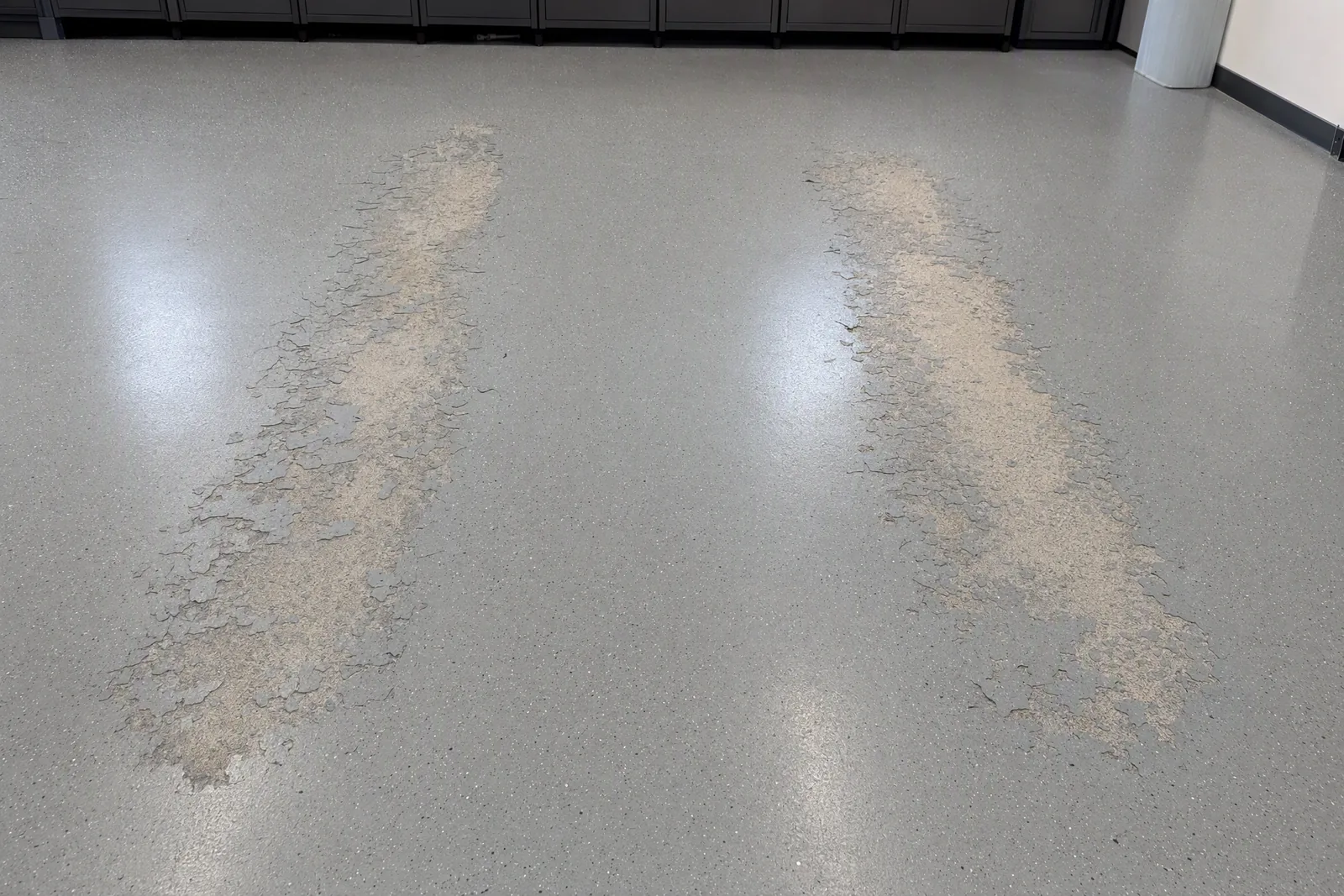 Garage floor coating lifted away in two tire-width patches from hot tire pickup