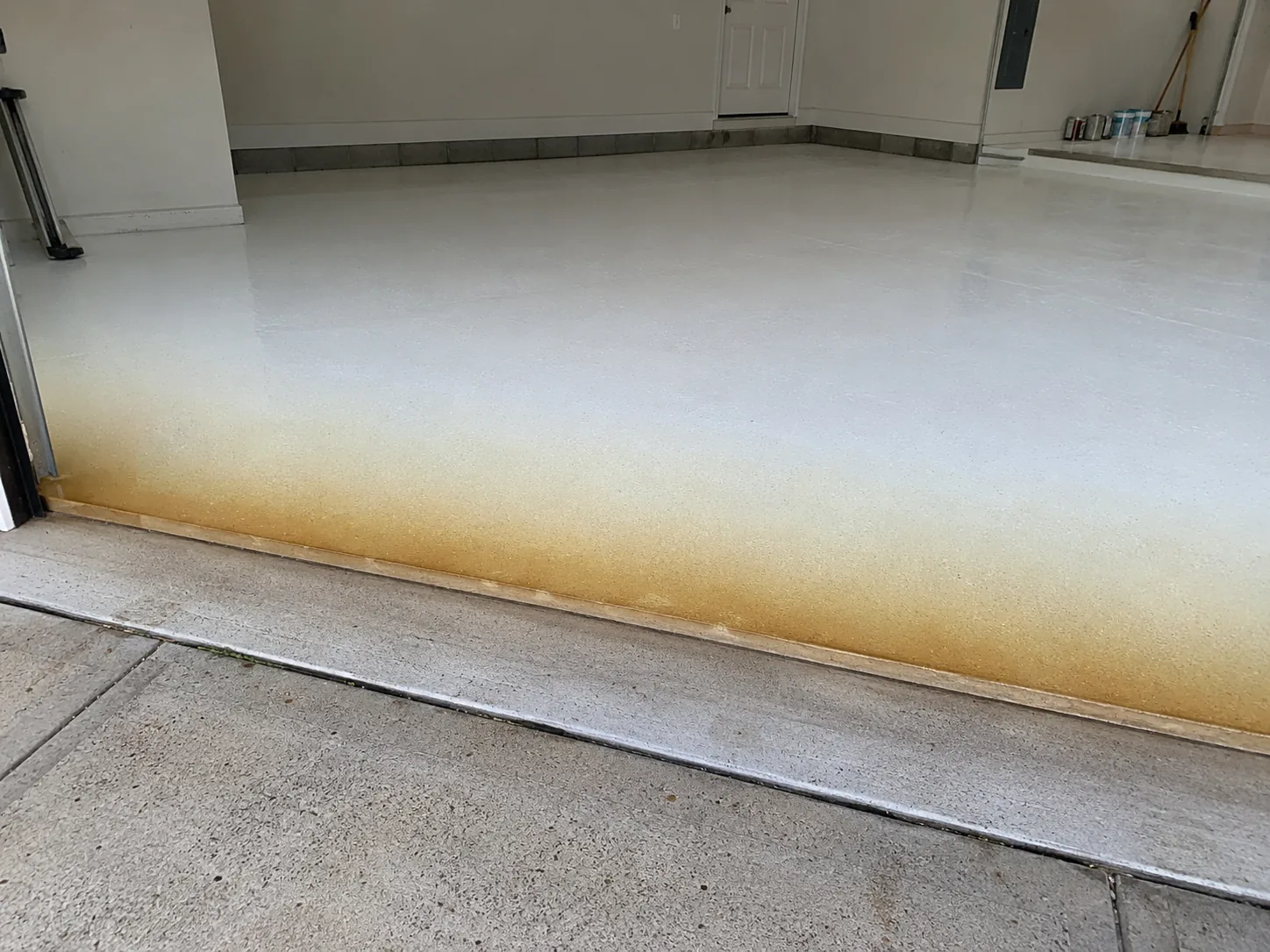 Epoxy floor coating ambered to yellow-brown near a garage door