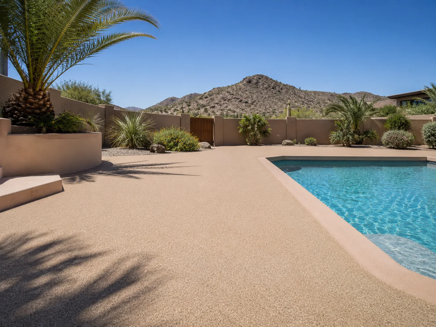Residential pool deck with textured tan quartz broadcast coating beside a swimming pool